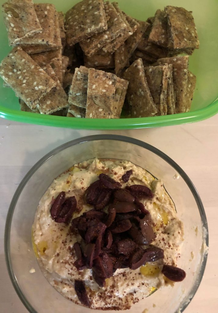hummus topped with olives and seedy crackers