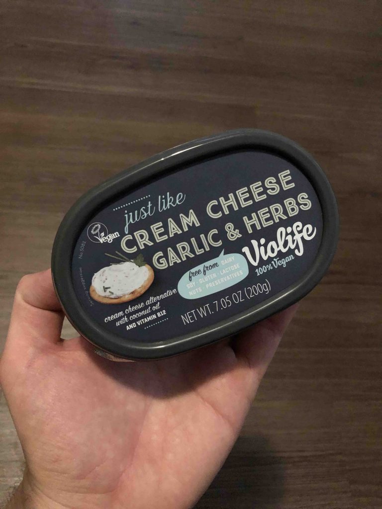 hand holding tub of cream cheese