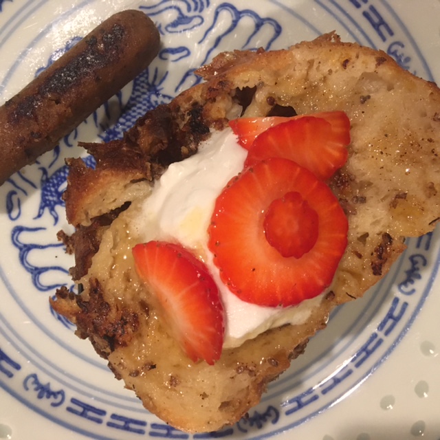 vegan French toast slice with cream and strawberries on top and sausage