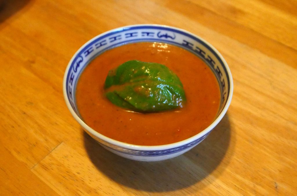 gaspacho in a small Chinese rice bowl with basil leaf on top