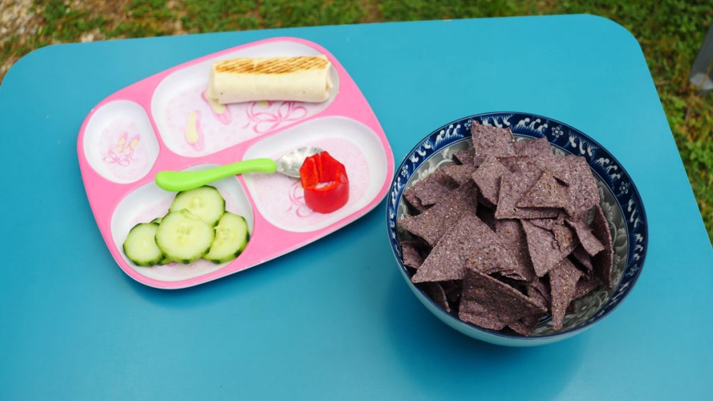 mini bean burrito, cucumber, and red bell pepper on pink child food tray